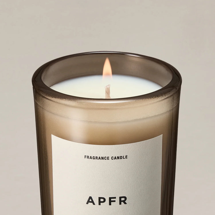 Lit APFR fragrance candle in a smoked glass vessel